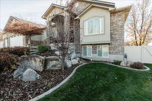 View of front facade featuring stone siding and stucco siding