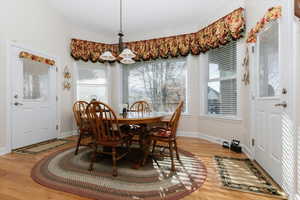 Dining area with healthy amount of natural light, light wood-style flooring, a chandelier, and lofted ceiling