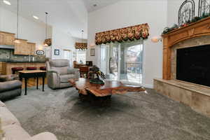 Living room with high vaulted ceiling, a premium fireplace, and carpet flooring