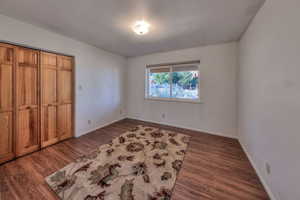 Unfurnished bedroom featuring a closet and dark wood-style flooring