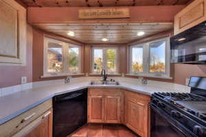 Kitchen with black appliances, light countertops, and brown cabinets