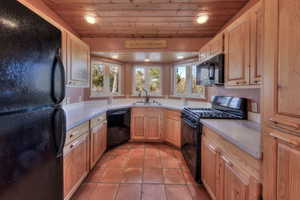 Kitchen featuring black appliances, wood ceiling, light countertops, light tile patterned flooring, and recessed lighting