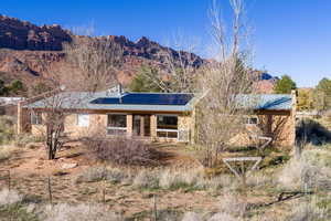 View of front facade with a mountain view, solar panels, a metal roof, a chimney, and a porch