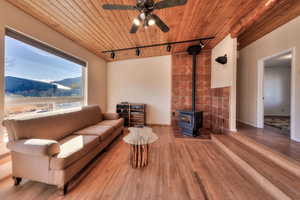 Living area featuring a wood stove, track lighting, wood ceiling, hardwood / wood-style flooring, and a mountain view
