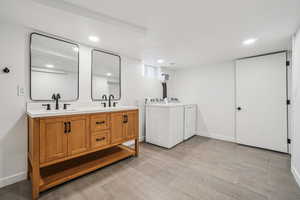 Laundry area featuring washing machine and dryer, wood finish floors, and recessed lighting