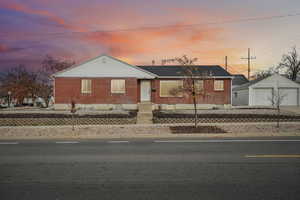 View of front of home featuring an outbuilding, a garage, and brick siding