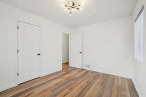 1597 - Unfurnished bedroom with a chandelier and light wood-style flooring