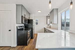 1597 - Kitchen featuring gray cabinets, pendant lighting, appliances with stainless steel finishes, and a peninsula