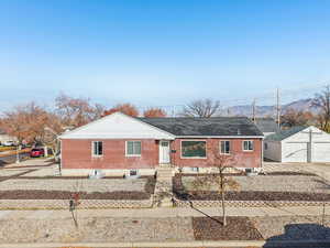View of front of property featuring an outdoor structure, a detached garage, brick siding, and a mountain view