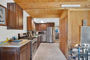 Kitchen with stainless steel appliances, wood ceiling, granite countertops, and wooden walls