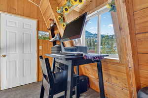 Office space featuring carpet floors, vaulted ceiling, wooden walls, and a mountain view