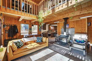 Living room featuring a wood burning stove, natural light, and a wooden ceiling with exposed beams