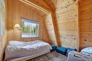 Bedroom featuring vaulted ceiling, wooden walls, and wood ceiling