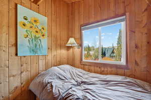 Bedroom with vaulted ceiling, wooden walls and mountain view
