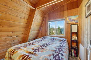 Carpeted bedroom featuring wood walls and wood ceiling
