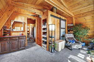 Loft space with wooden walls, carpet floors, and wooden ceiling