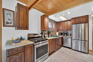 Kitchen with stainless steel appliances, wooden ceiling, Cherry cabinets, granite countertops and natural lighting