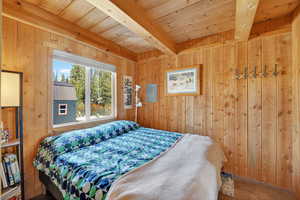 Primary Bedroom with a wooden ceiling, exposed beams and wood walls