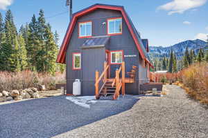 View of front facade with a metal roof, a forest view, and a mountain view