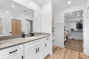 Bathroom featuring a walk in closet, vanity, recessed lighting, a shower with curtain, and light wood-type flooring