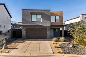 Contemporary home featuring stucco siding, concrete driveway, stone siding, an attached garage, and a porch