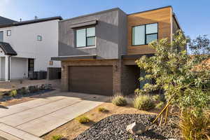 Modern home featuring an attached garage, brick siding, concrete driveway, and stucco siding