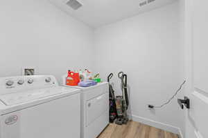 Laundry area with light wood finished floors and independent washer and dryer