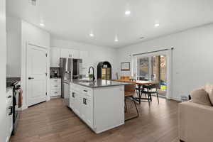 Kitchen featuring white cabinetry, a kitchen island with sink, dark wood-style floors, appliances with stainless steel finishes, and recessed lighting
