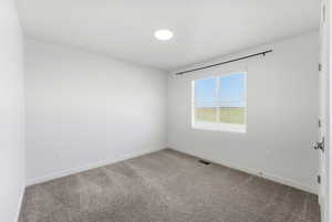 Carpeted spare room featuring baseboards