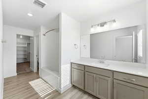 Full bath with a walk in closet, vanity, tub / shower combination, light wood-style floors, and recessed lighting