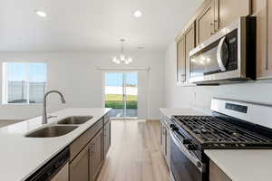 Kitchen featuring appliances with stainless steel finishes, pendant lighting, light wood-style flooring, recessed lighting, and light stone countertops