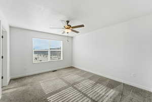 Empty room featuring carpet, ceiling fan, and a textured ceiling
