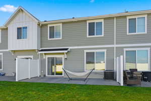 Rear view of property featuring board and batten siding, a patio, and a lawn