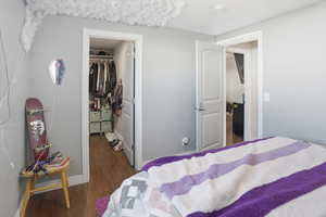 Bedroom featuring dark wood-style flooring and a spacious closet