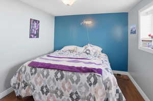 Bedroom with dark wood finished floors and an accent wall