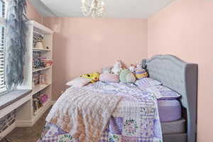 Carpeted bedroom with a chandelier and baseboards