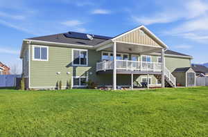 Rear view of property with stairs, a ceiling fan, a wooden deck, a storage shed, and roof mounted solar panels