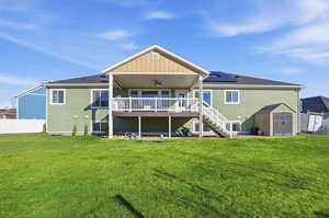 Rear view of property featuring ceiling fan, a shed, stairs, a wooden deck, and solar panels
