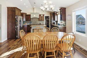 Dining room with a chandelier, vaulted ceiling, dark wood finished floors, and recessed lighting