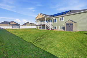 Back of property featuring a trampoline, stairs, a storage unit, a patio area, and roof mounted solar panels
