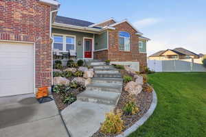 Entrance to property featuring covered porch, brick siding, a garage, a shingled roof, and board and batten siding