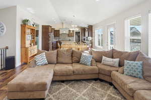 Living area featuring a chandelier, vaulted ceiling, wood finished floors, and recessed lighting