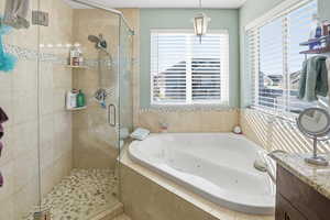 Full bath featuring a tub with jets, a shower stall, and vanity