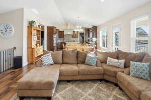 Living room featuring lofted ceiling, a chandelier, wood finished floors, and recessed lighting