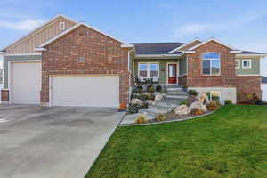View of front of home featuring a front lawn, an attached garage, driveway, brick siding, and roof with shingles