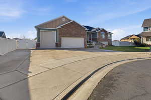 View of front of house featuring brick siding, a gate, concrete driveway, and a garage