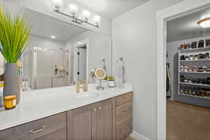 Full bathroom with a stall shower, a walk in closet, vanity, and light colored carpet