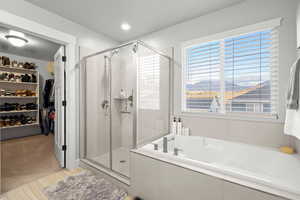 Bathroom featuring a spacious closet, a garden tub, a shower stall, recessed lighting, and light carpet