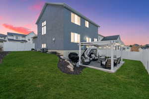 Back of house at dusk with an outdoor living space, a fenced backyard, a pergola, a patio, and stucco siding