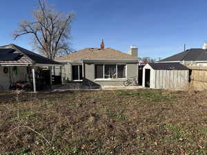 Back of house with a storage shed, a patio, brick siding, a chimney, and a fenced backyard